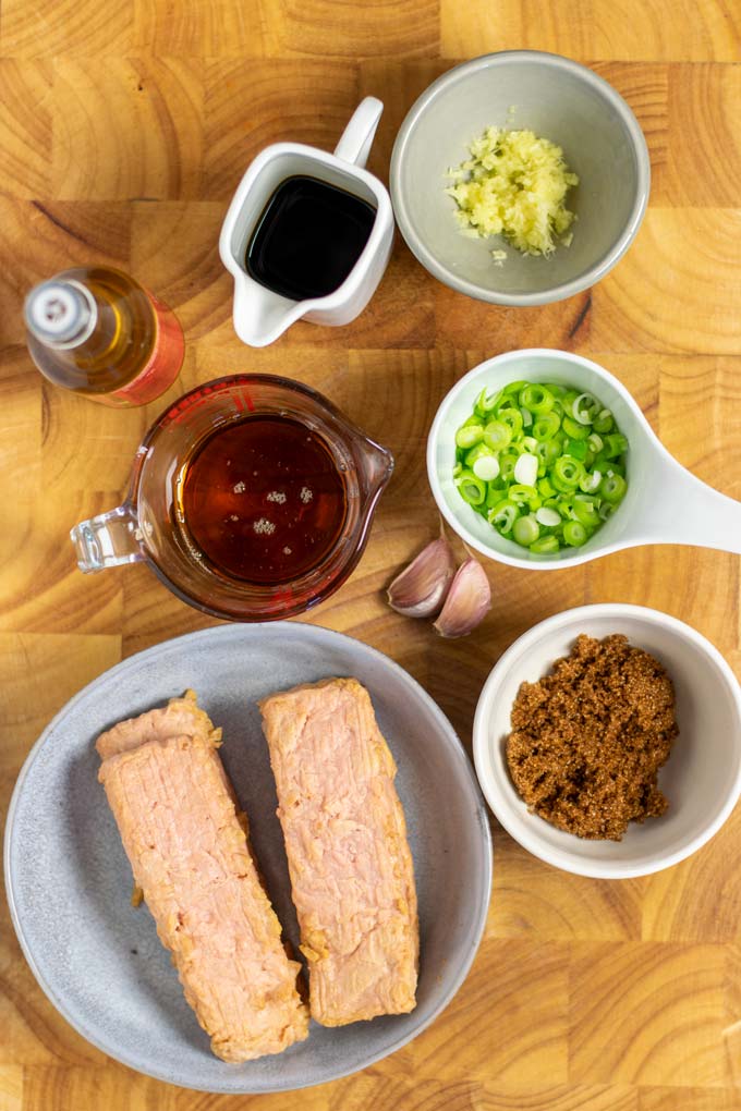Ingredients needed to make Teriyaki Salmon are collected on a wooden board.