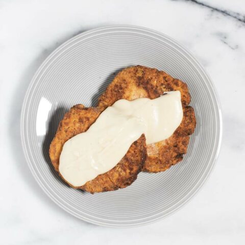 Two Country Fried Steaks are served on a plate with some gravy.