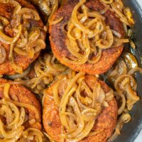 Closeup of Hamburger Steaks with onion gravy in a pan.