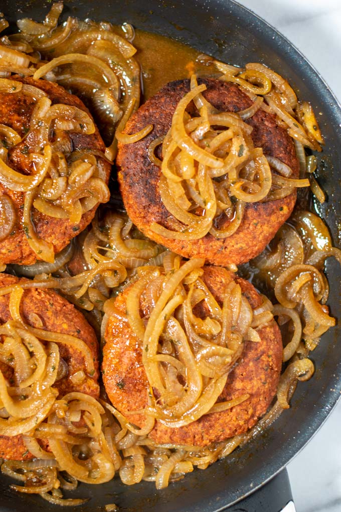 Closeup of Hamburger Steaks with onion gravy in a pan.