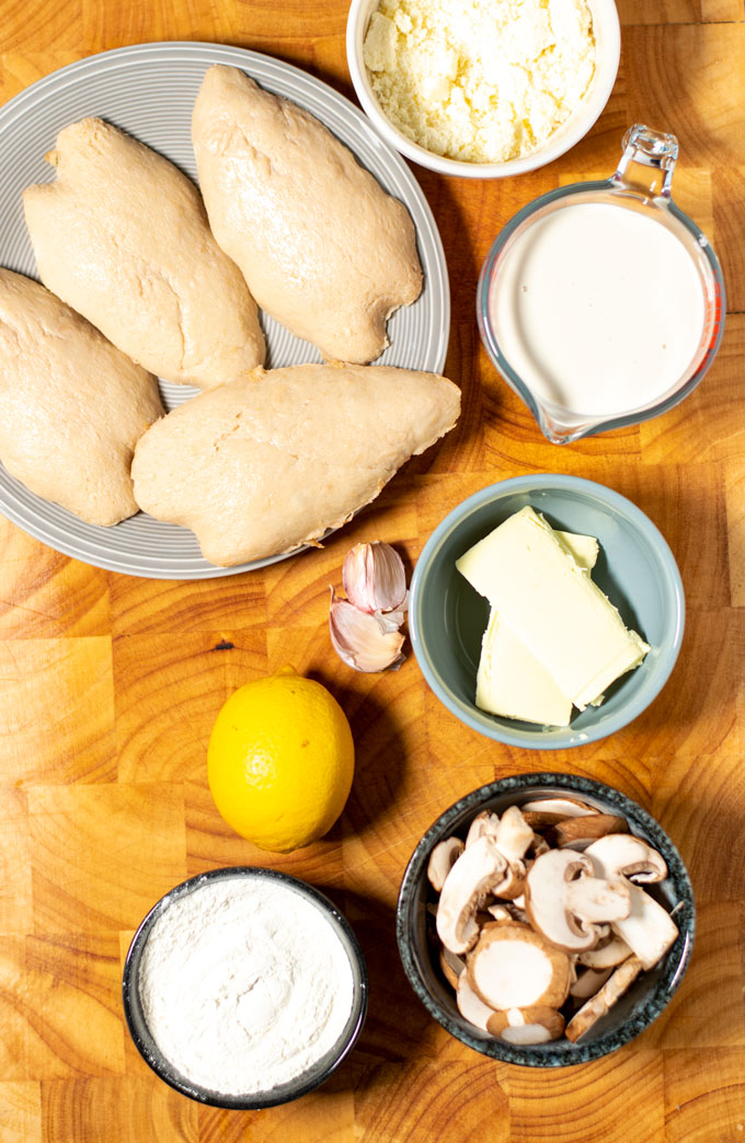 Ingredients needed for Mushroom Chicken are collected on a wooden board.