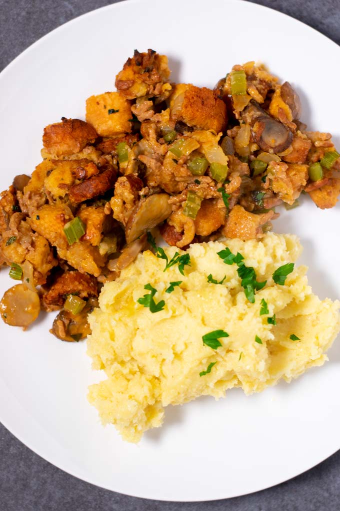 A serving of the Mushroom Stuffing on a white plate with mashed potatoes.