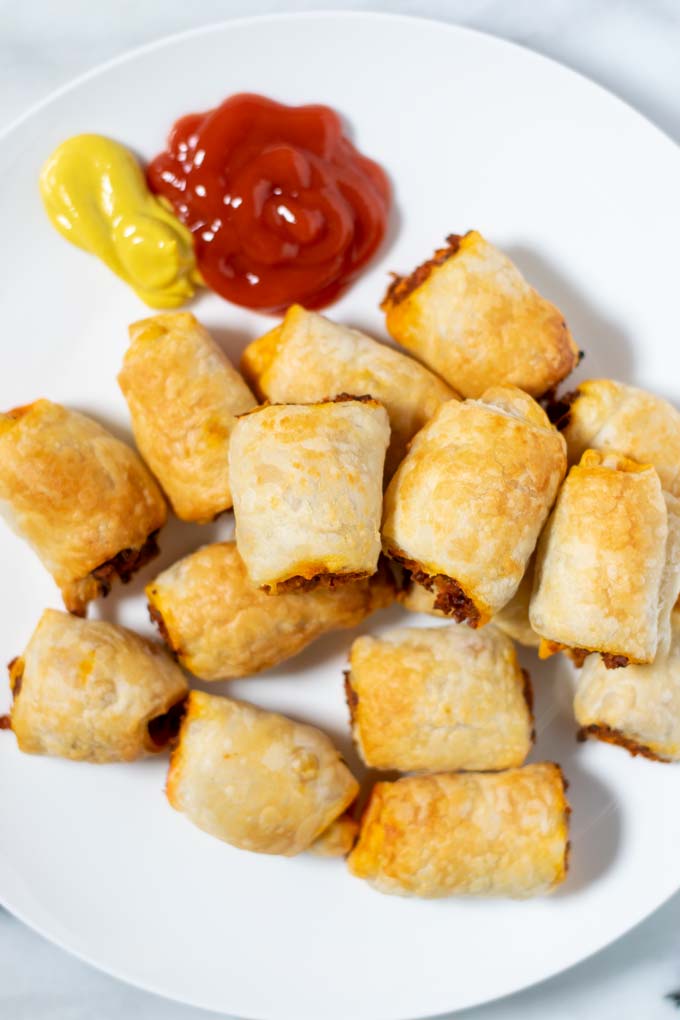 Sausage Rolls on a serving plate, with ketchup and mustard as sides.