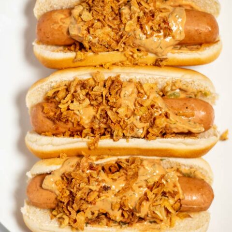 Closeup of three Hot Dogs on a white plate.