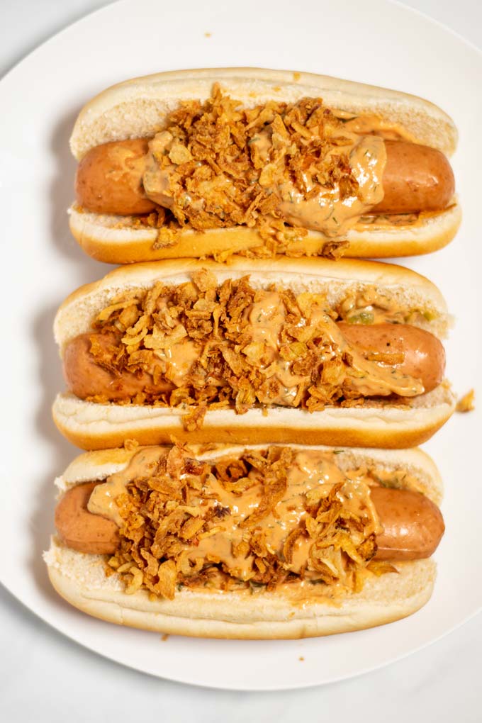 Closeup of three Hot Dogs on a white plate.