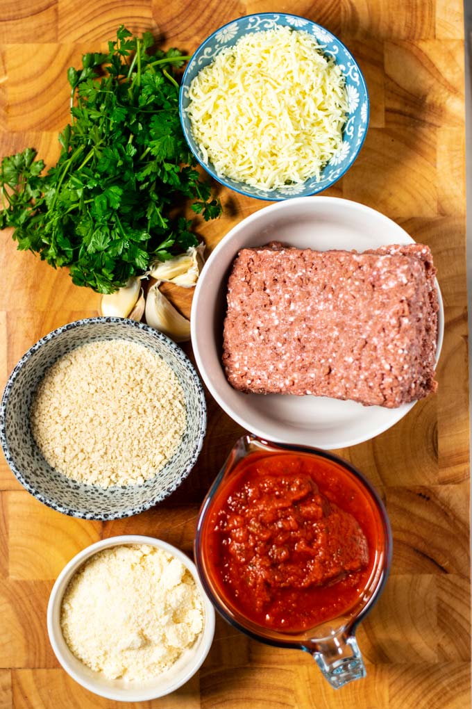 Ingredients needed for making Meatball Bake assembled on a wooden board.