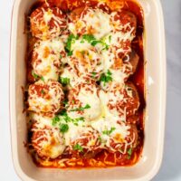 Closeup of Meatball Bake in a casserole dish, garnished with fresh parsley.