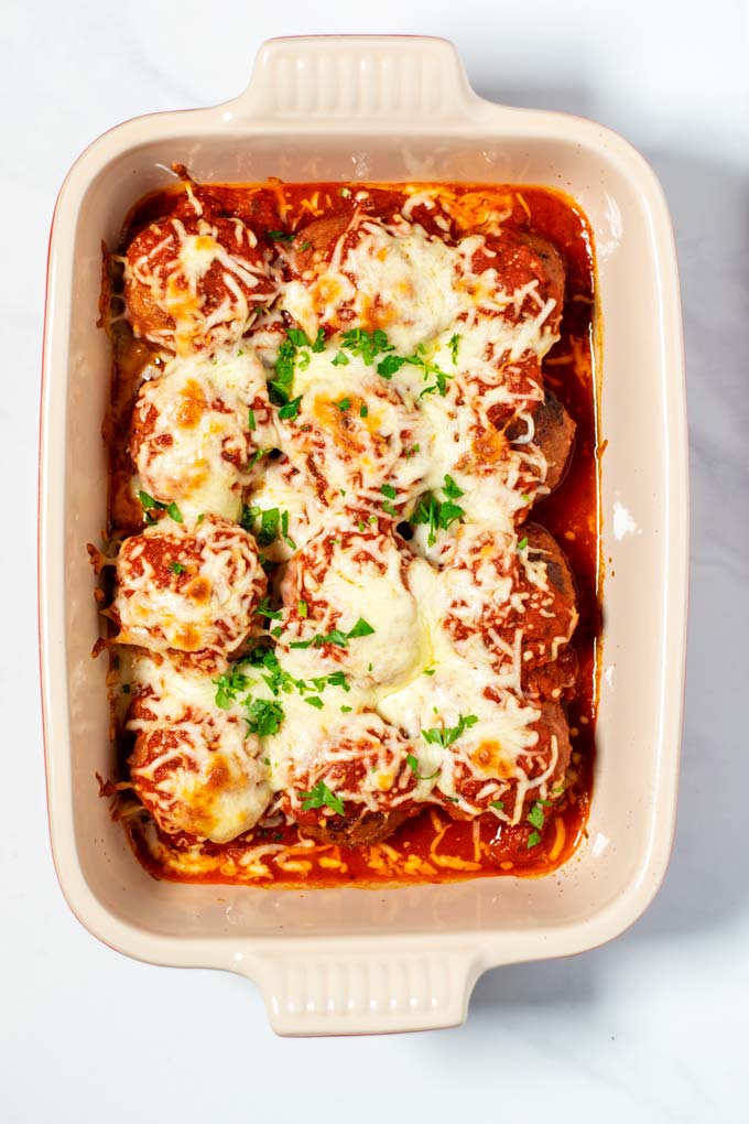 Closeup of Meatball Bake in a casserole dish, garnished with fresh parsley.