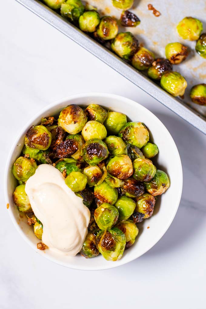 A portion of Roasted Brussels Sprouts served with vegan mayonnaise.