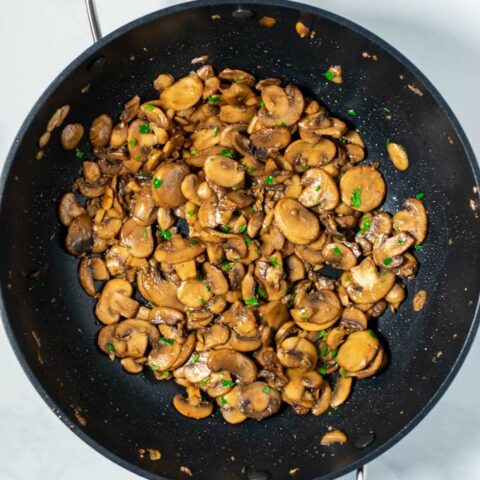 Top view of a large pan with the Sautéed Mushrooms, garnished with fresh parsley.