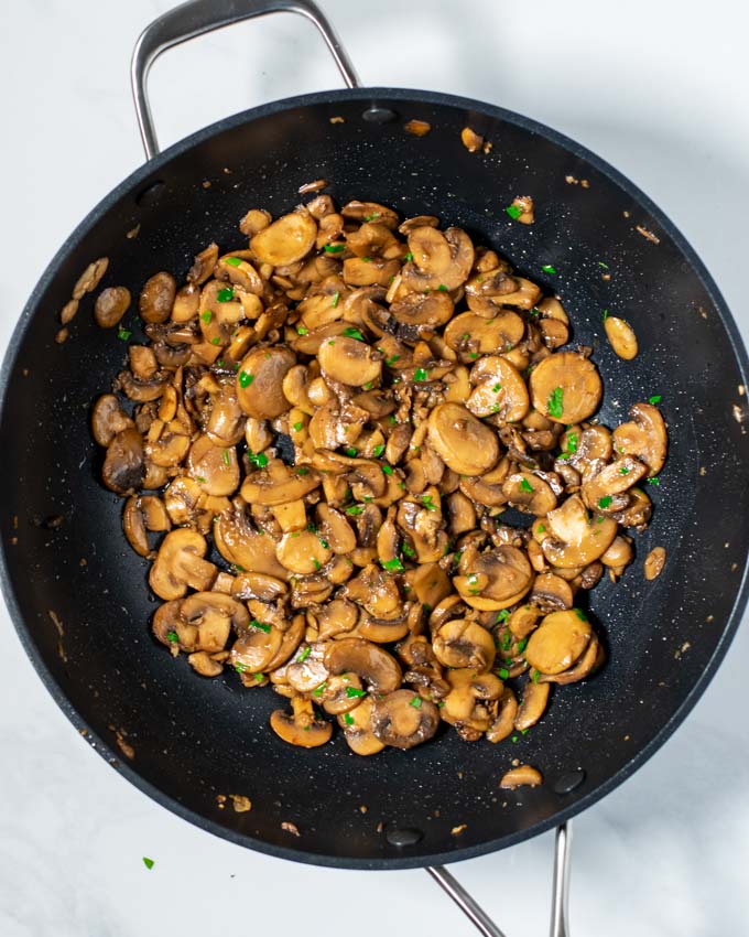 Top view of a large pan with the Sautéed Mushrooms, garnished with fresh parsley.