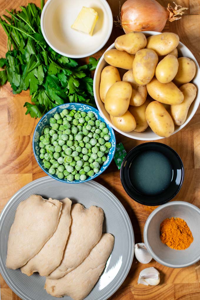 Ingredients needed for making Chicken Vesuvio are assembled on a wooden board.