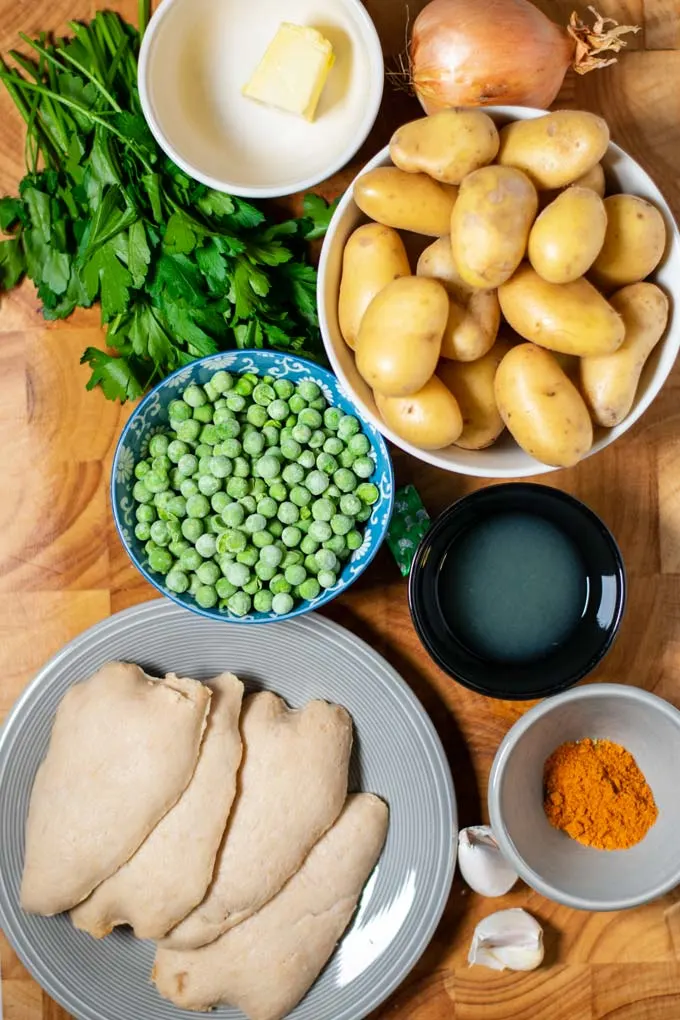 Ingredients needed for making Chicken Vesuvio are assembled on a wooden board.