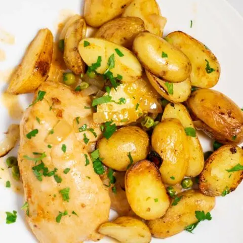 Top view of a portion of Chicken Vesuvio, served in a white plate.