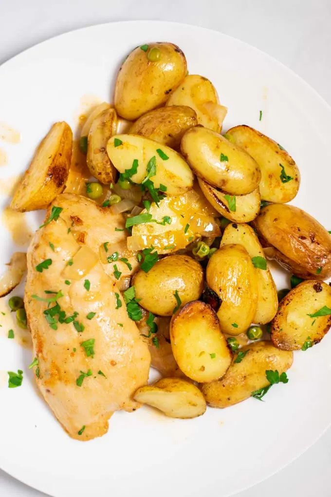 Top view of a portion of Chicken Vesuvio, served in a white plate.