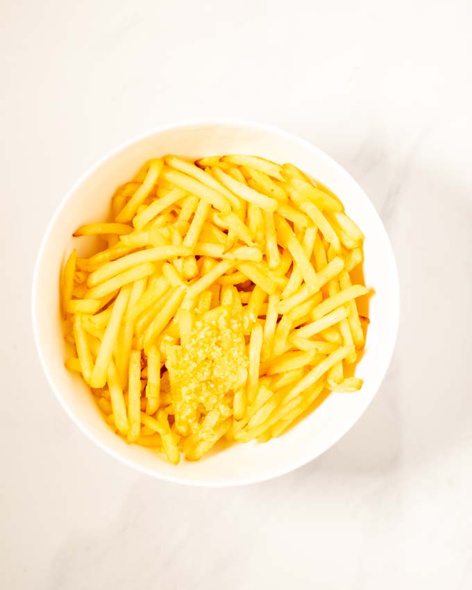 Top view of a bowl of fries with the garlic sauce given over them.