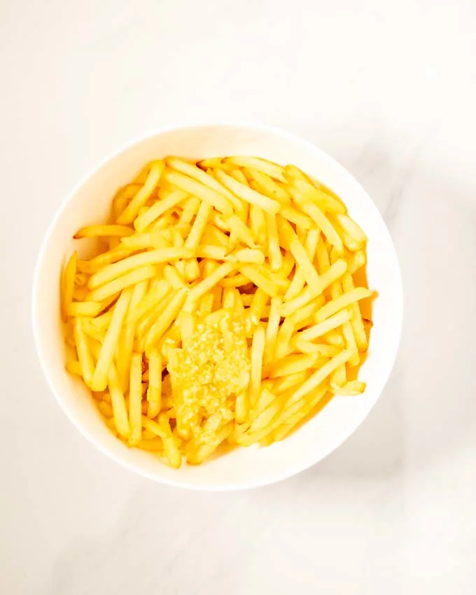 Top view of a bowl of fries with the garlic sauce given over them.
