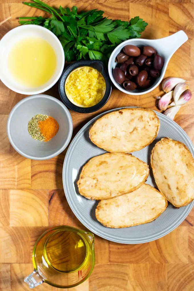 Ingredients needed for making Greek Chicken are collected on a wooden board.