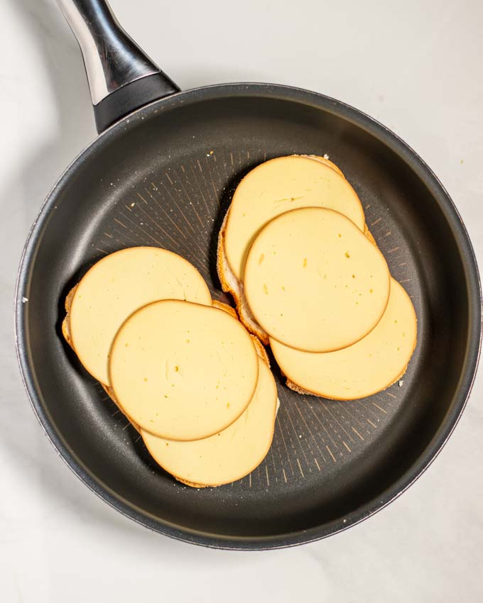 Cheese slices are given on top of the bread in the pan.