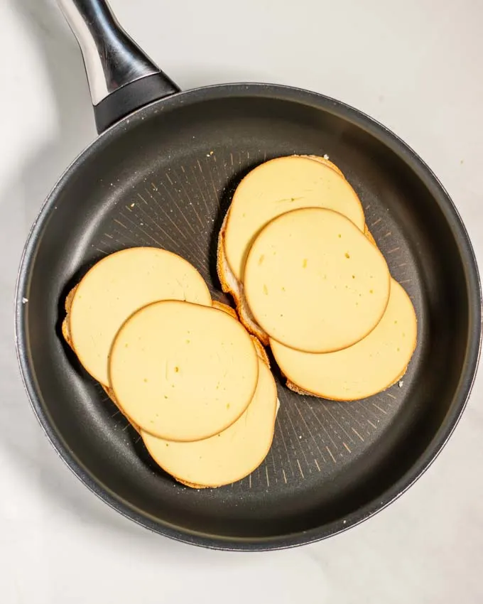 Cheese slices are given on top of the bread in the pan.