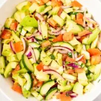 Closeup on a salad bowl with the Avocado Salad, showing the avocados, cucumbers, tomatoes and onions in the easy dressing.