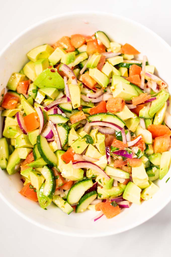 Closeup on a salad bowl with the Avocado Salad, showing the avocados, cucumbers, tomatoes and onions in the easy dressing.