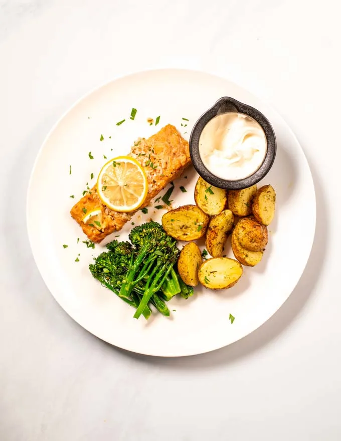 View of a portion of Baked Salmon served with roasted potatoes, and broccoli.