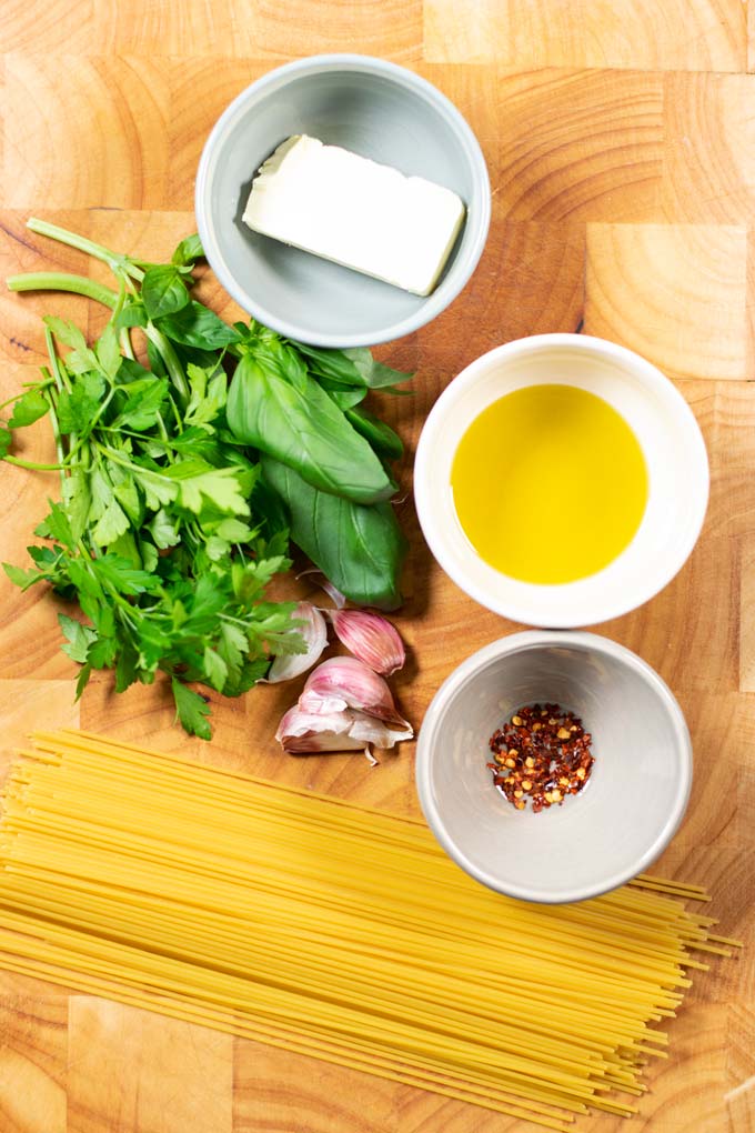 Ingredients needed for making Garlic Pasta is assembled on a wooden board.