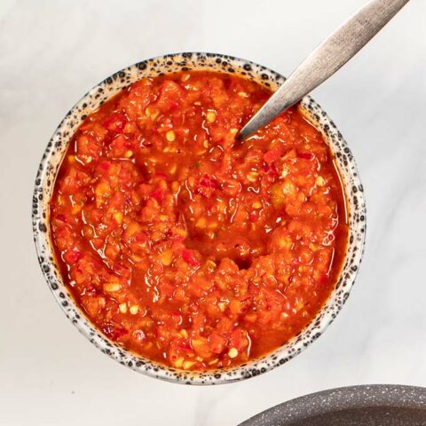 Closeup of a serving bowl with Peri Peri Sauce with a small spoon.