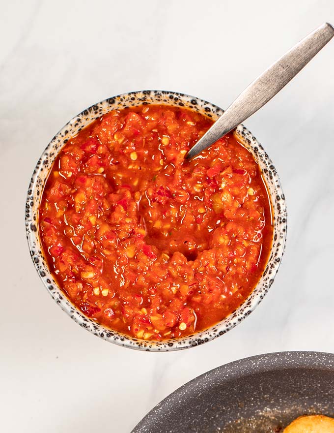 Closeup of a serving bowl with Peri Peri Sauce with a small spoon.