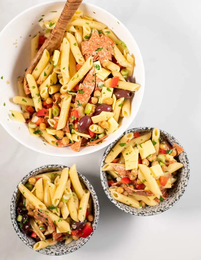 Two portions of Antipasto Salad are served in small bowls, the big serving bowl is in the background.