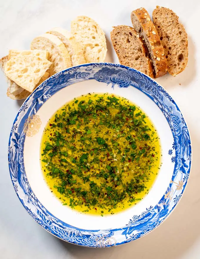 Bread Dipping Oil served on a plate with some bread in the background.