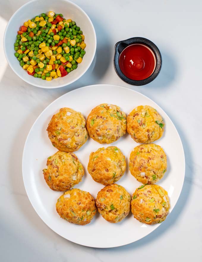 Nine Cheese Puffs are served with some fresh vegetables and a side of ketchup.