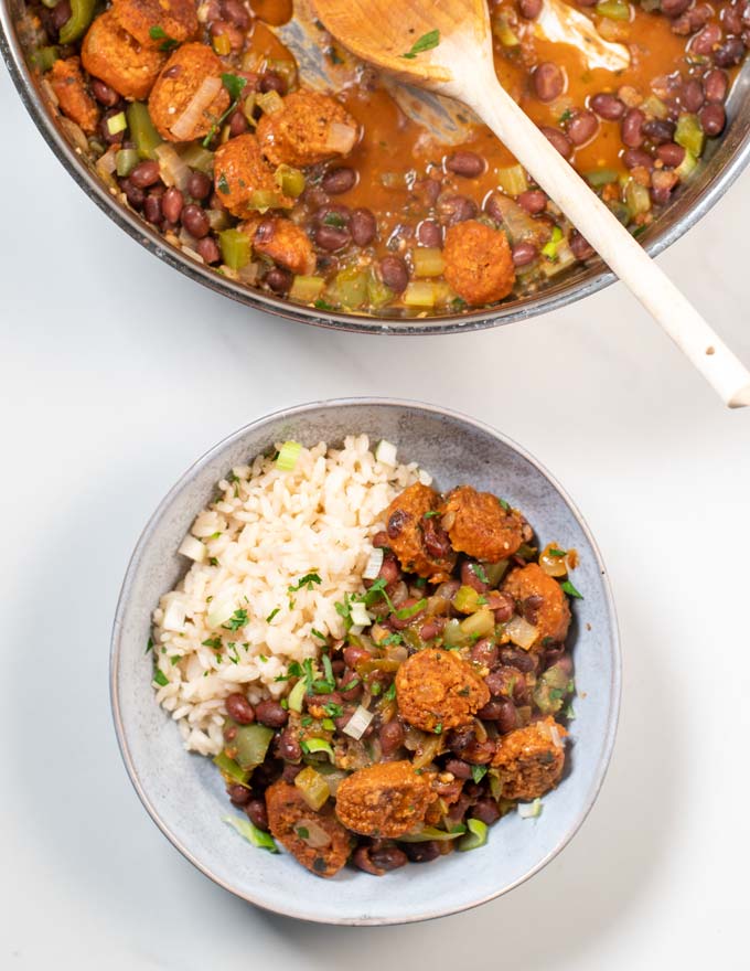 A portion of Red Beans and Rice in a bowl, with a large pot in the background.