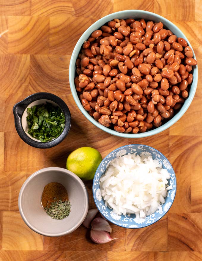 Ingredients needed for making Refried Beans are collected on a wooden board.