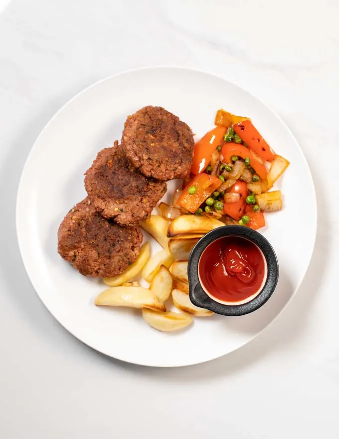 A portion of Sausage Patties served with potato badges and fried vegetables.