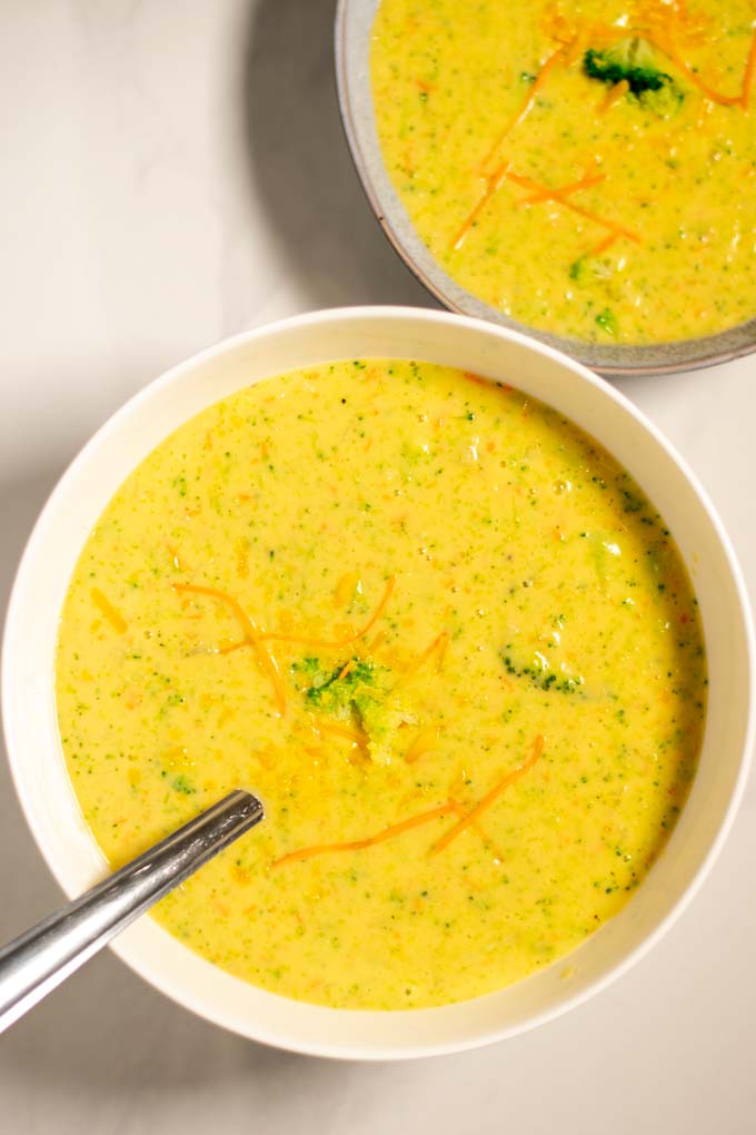 Portions of Broccoli Cheddar Soup are served in white bowls.