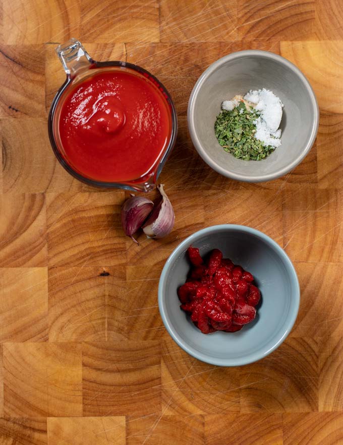 Ingredients needed to make Pizza Sauce are assembled on a wooden board.