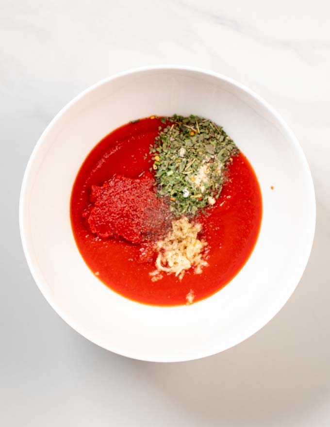 A top view of a mixing bowl with all the ingredients of Pizza Sauce.