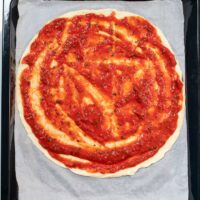 A homemade pizza is covered in Pizza Sauce.