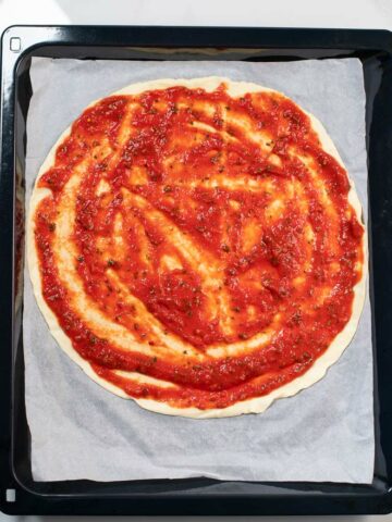 A homemade pizza is covered in Pizza Sauce.