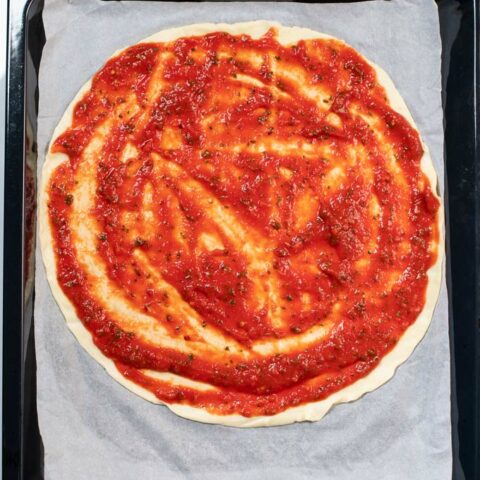 A homemade pizza is covered in Pizza Sauce.