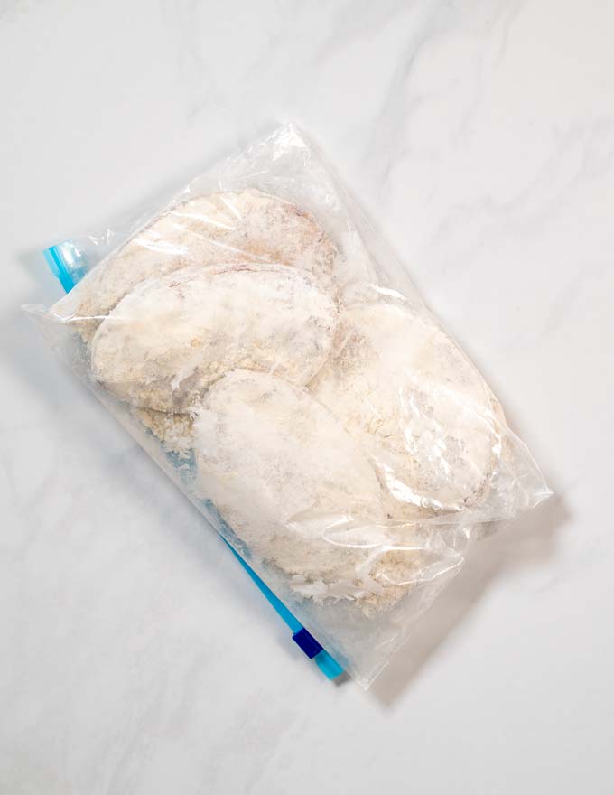 Chicken filets are dredged in flour using a ziploc bag.