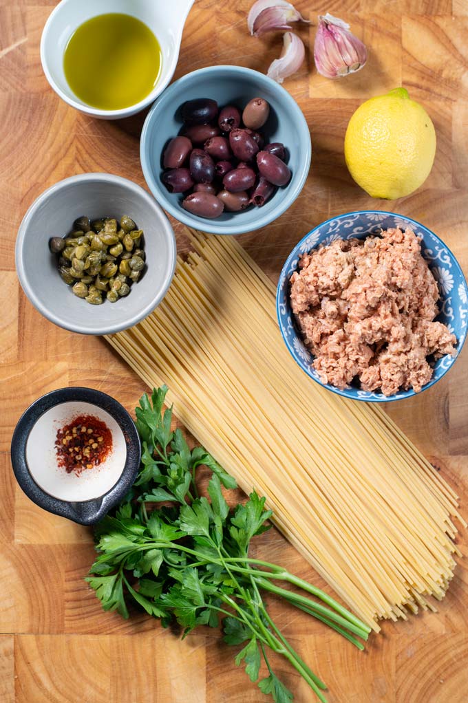 Ingredients needed for making Tuna Pasta are collected on a wooden board.