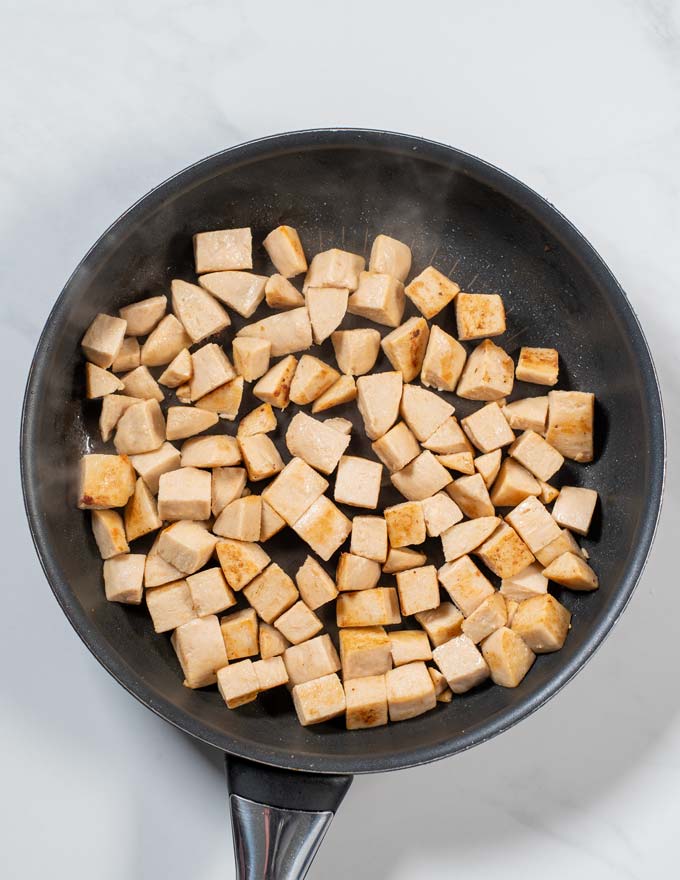 Top view of a pan with vegan chicken cut in cubes being fried.