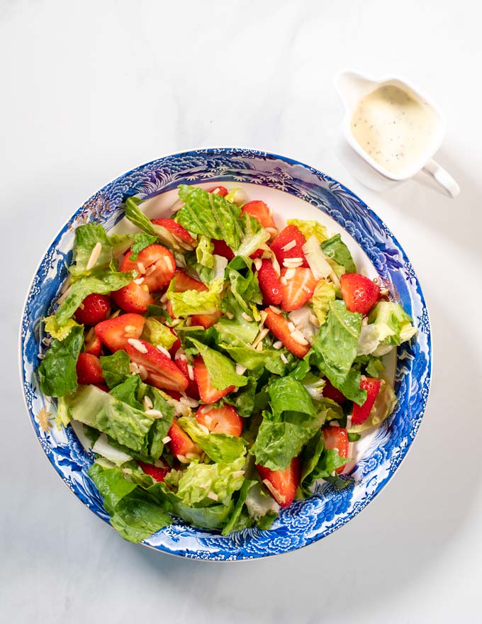 A large plate with fresh salad and a small jar with Poppy Seed Dressing.