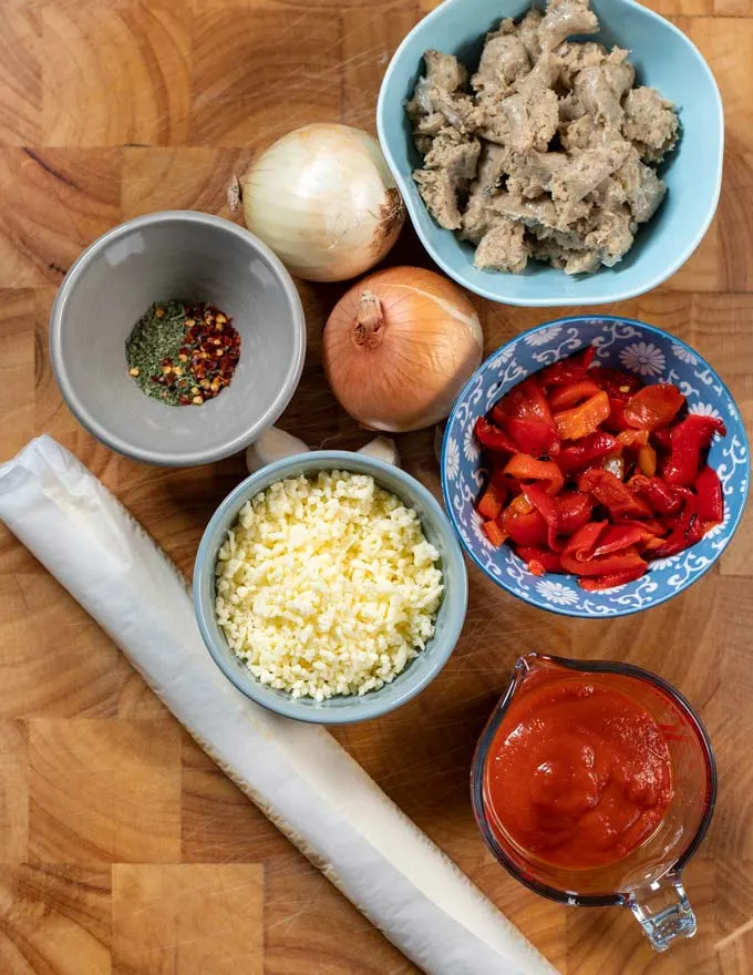 Ingredients needed for making Sausage Pizza are assembled on a board.