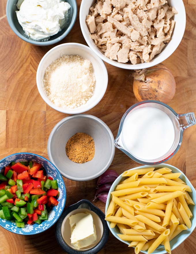 Ingredients needed for making Cajun Chicken Pasta is assembled on a board.