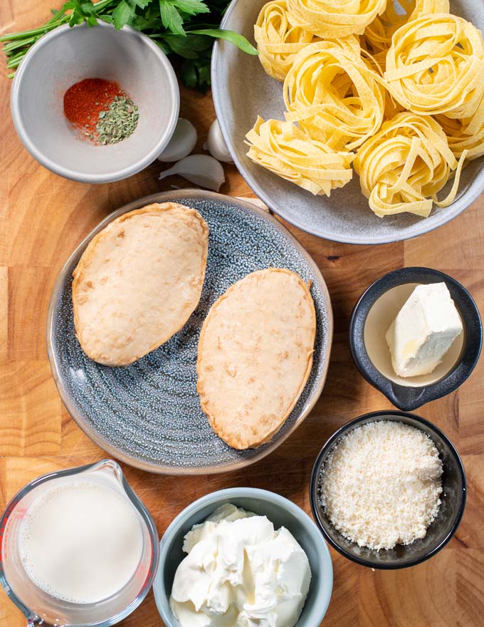 Ingredients needed for Chicken Alfredo are collected on a board.