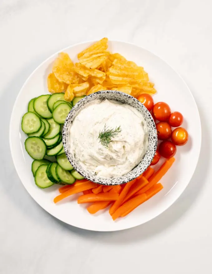Top view on a serving of Dill Dip with a vegetable and chips platter.